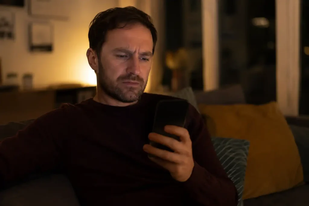 A player on a sofa reacting to a declined Skrill casino deposit on a phone