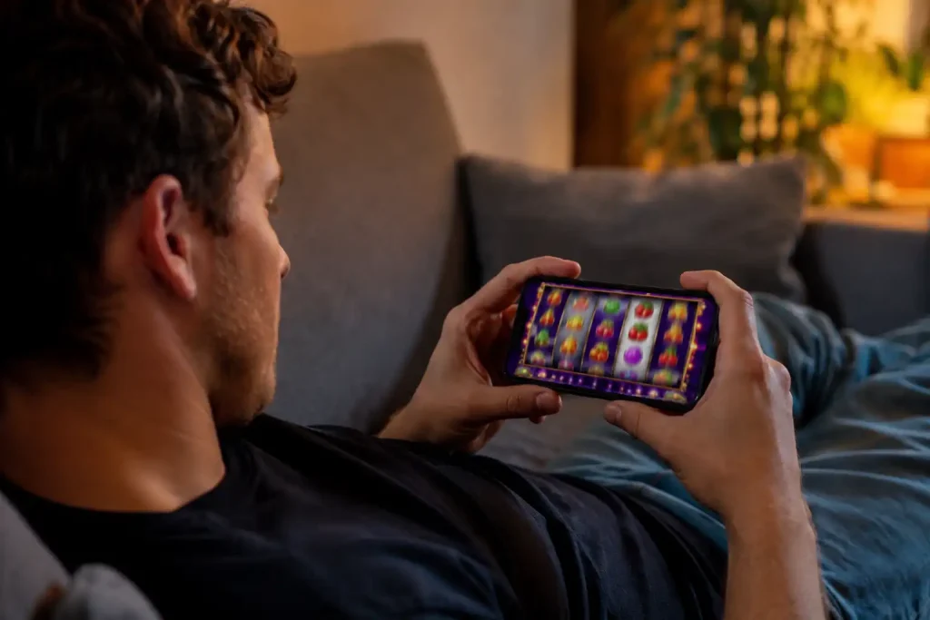 A young adult using the Skrill app to play casino games on a phone